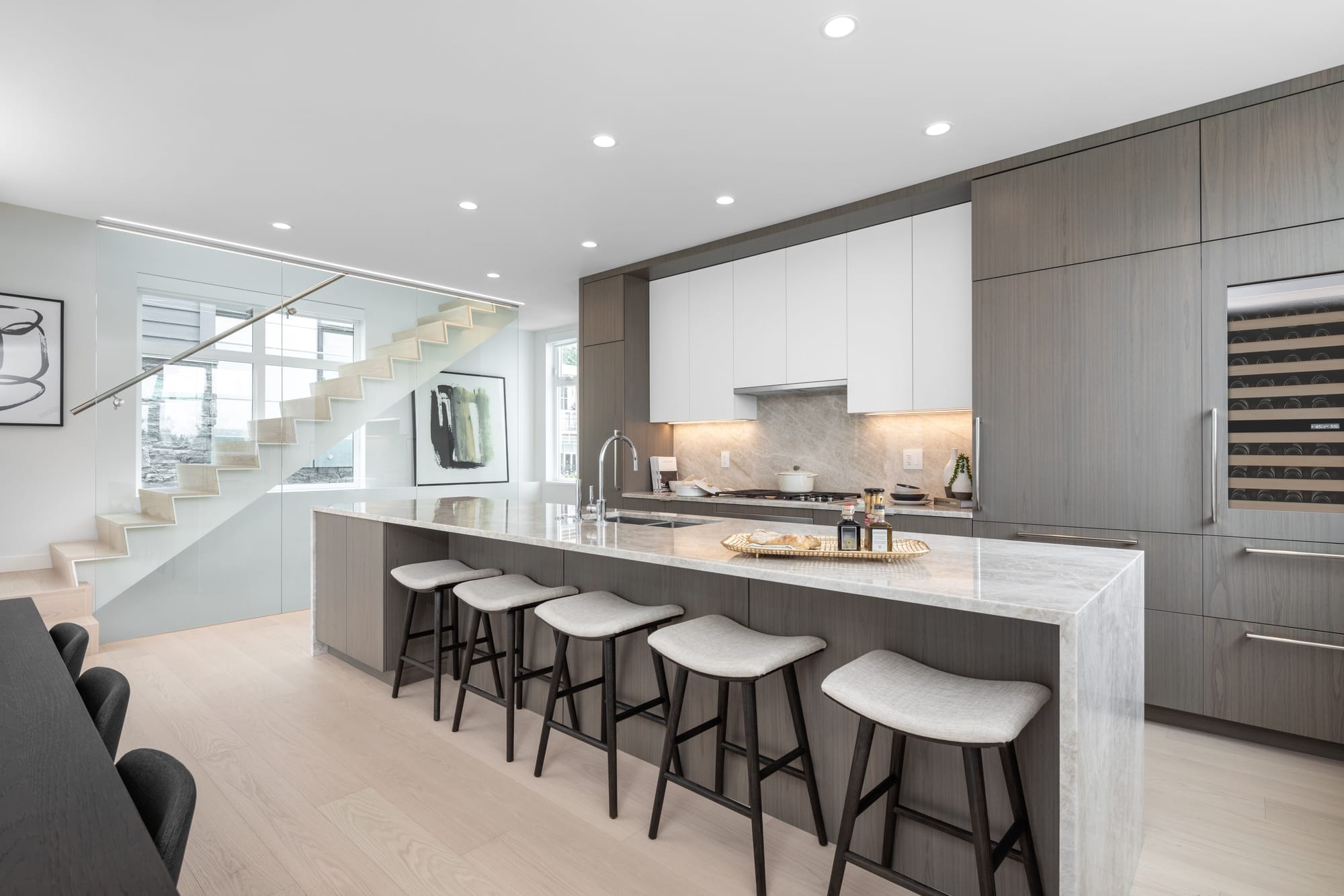 Single-family home kitchen with island and floating staircase at Evelyn, West Vancouver